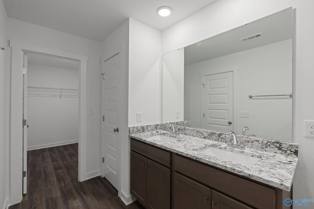 full bath featuring double vanity, visible vents, wood finished floors, and a sink