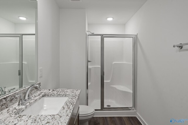 bathroom with wood finished floors, toilet, a stall shower, and vanity