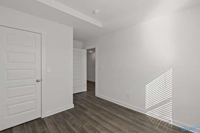 empty room featuring dark wood-type flooring and baseboards