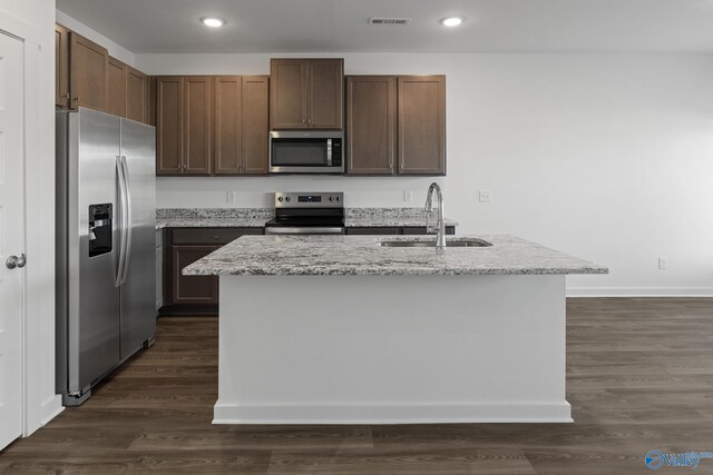 kitchen featuring visible vents, a sink, dark wood finished floors, stainless steel appliances, and light stone countertops