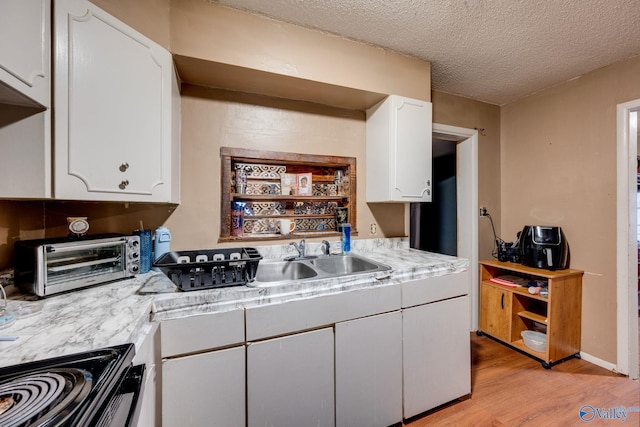 kitchen with sink, white cabinets, light hardwood / wood-style floors, black electric range, and a textured ceiling