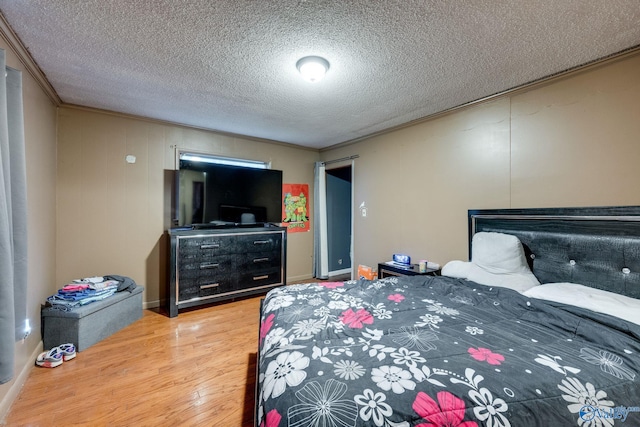 bedroom with wood-type flooring, ornamental molding, and a textured ceiling