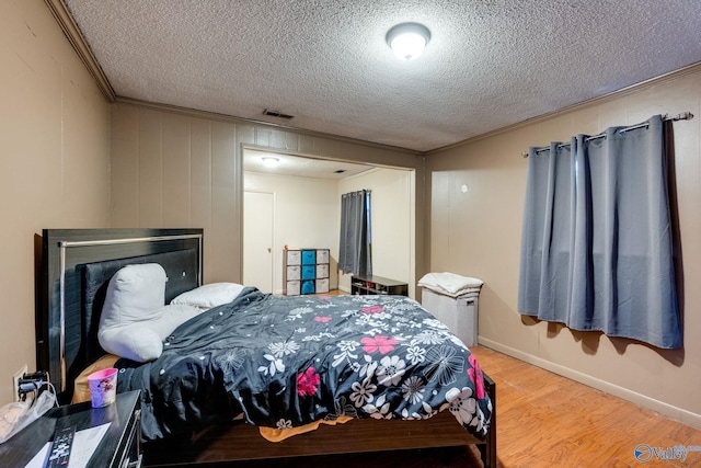 bedroom with crown molding, hardwood / wood-style floors, and a textured ceiling