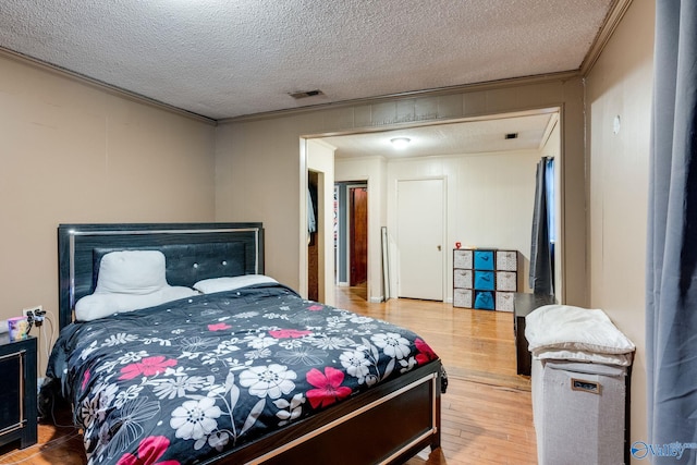 bedroom with crown molding, wood-type flooring, and a textured ceiling