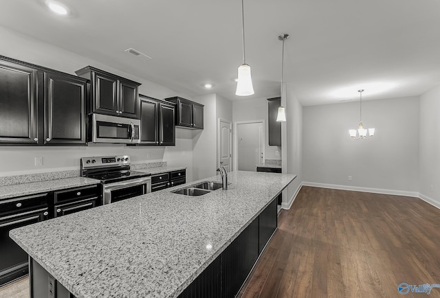 kitchen with a sink, an island with sink, dark wood-style flooring, appliances with stainless steel finishes, and dark cabinets