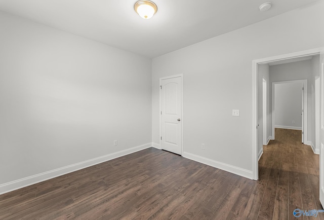 unfurnished bedroom with baseboards and dark wood-style flooring