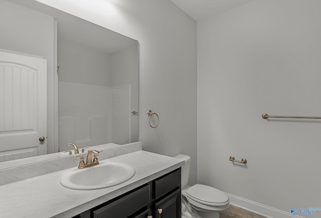 bathroom with vanity, toilet, a shower, and baseboards