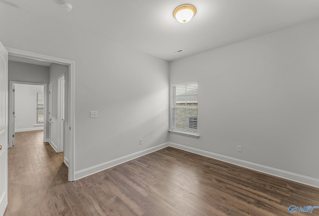 unfurnished room featuring visible vents, baseboards, and dark wood-style floors