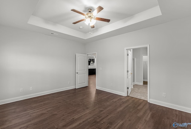 unfurnished bedroom with dark wood finished floors, a raised ceiling, visible vents, and baseboards