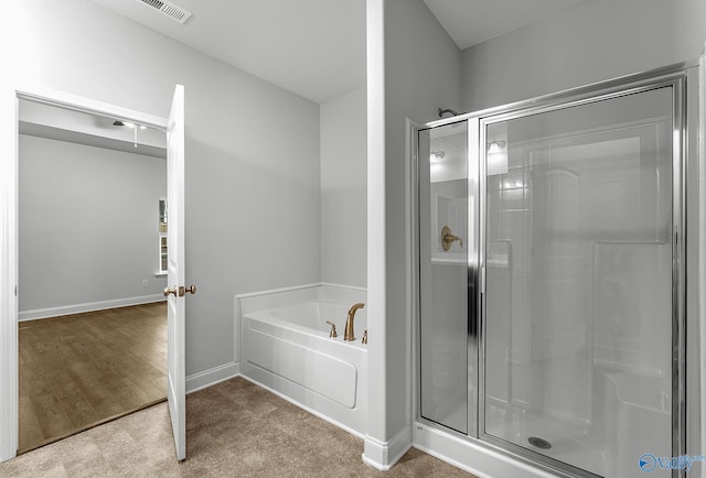 bathroom featuring a shower stall, a garden tub, baseboards, and visible vents