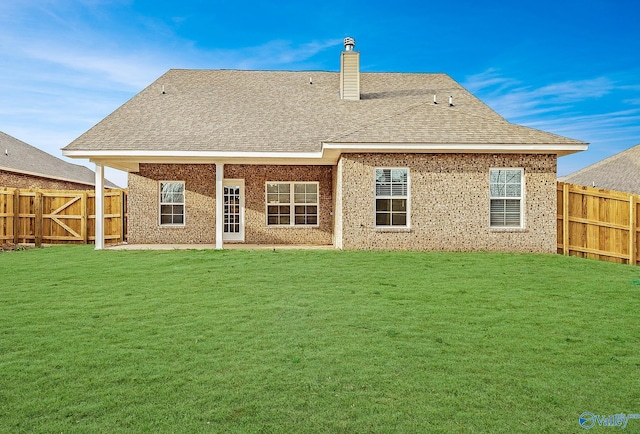 rear view of property featuring a fenced backyard, a chimney, a yard, and a shingled roof