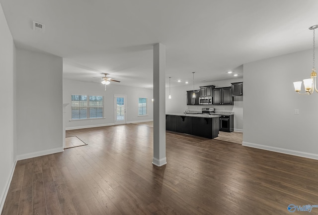 unfurnished living room featuring dark wood-style floors, visible vents, baseboards, recessed lighting, and ceiling fan with notable chandelier