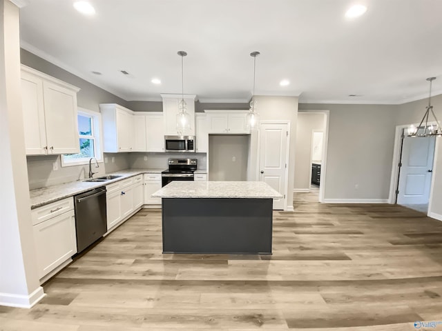 kitchen featuring sink, a center island, hanging light fixtures, appliances with stainless steel finishes, and white cabinets