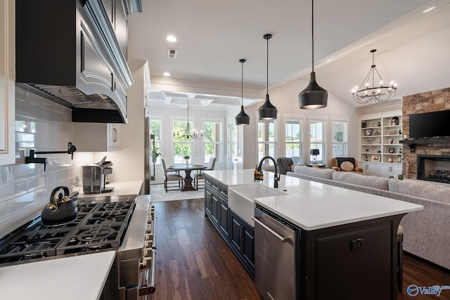 kitchen with pendant lighting, dishwasher, an island with sink, sink, and a notable chandelier