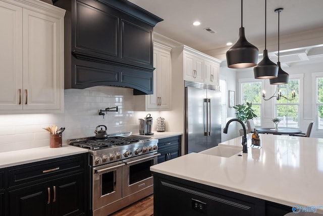 kitchen featuring pendant lighting, tasteful backsplash, white cabinetry, sink, and premium appliances