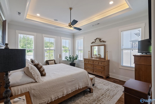 bedroom with dark hardwood / wood-style floors, ceiling fan, a tray ceiling, and crown molding