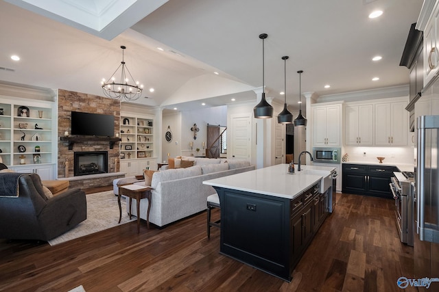 kitchen with premium appliances, a kitchen breakfast bar, a center island with sink, and white cabinets