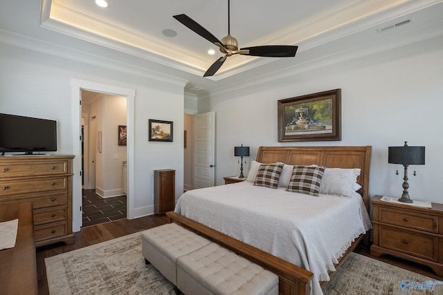 bedroom with crown molding, dark hardwood / wood-style floors, ceiling fan, and a tray ceiling