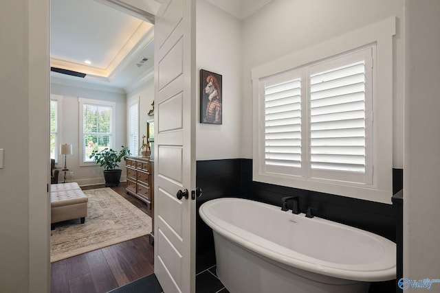 bathroom featuring a washtub, hardwood / wood-style flooring, vanity, ornamental molding, and a raised ceiling