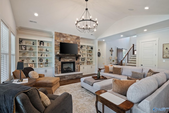 living room with lofted ceiling, crown molding, built in features, a fireplace, and light wood-type flooring