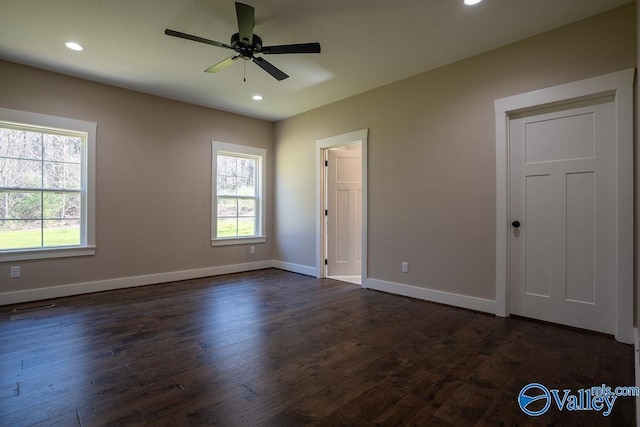 unfurnished bedroom with baseboards, multiple windows, and dark wood-style flooring