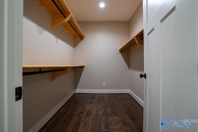 walk in closet with dark wood-style floors