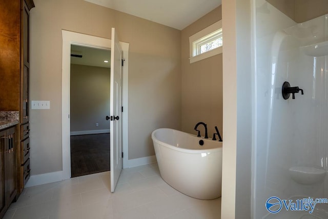 bathroom featuring vanity, tile patterned floors, baseboards, and a freestanding bath