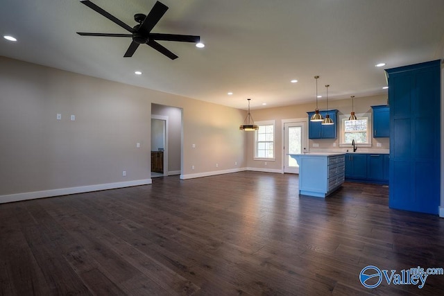 unfurnished living room with dark wood-type flooring, baseboards, ceiling fan, recessed lighting, and a sink