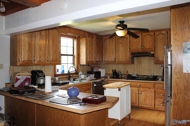 kitchen with ventilation hood, a sink, black appliances, and brown cabinetry