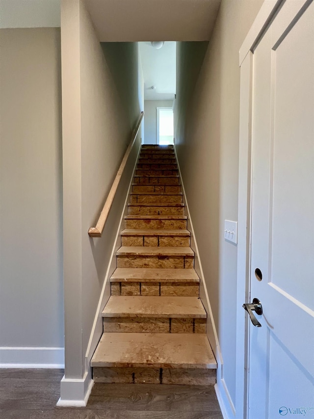 staircase with baseboards and wood finished floors