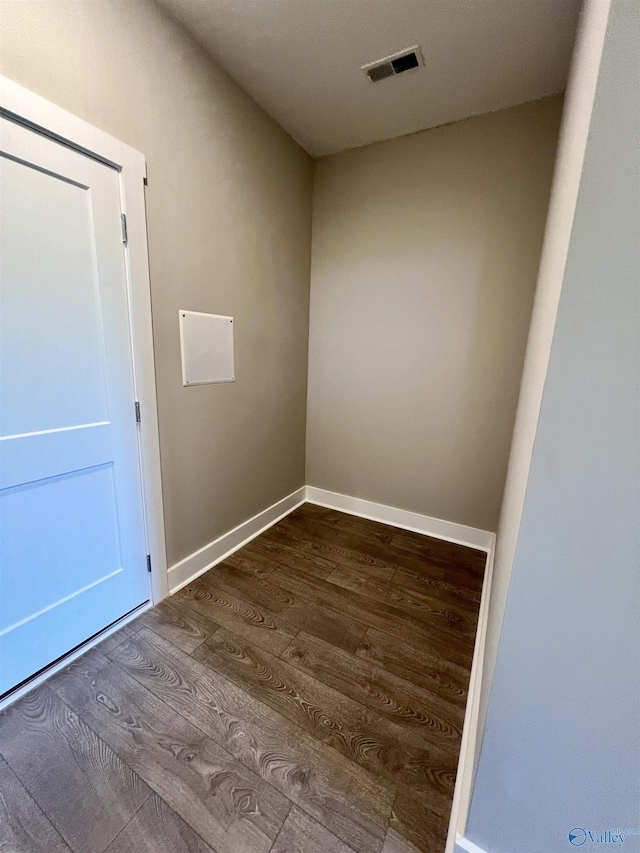 empty room with dark wood-style flooring, visible vents, and baseboards