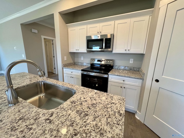 kitchen featuring a sink, white cabinetry, appliances with stainless steel finishes, dark wood finished floors, and crown molding