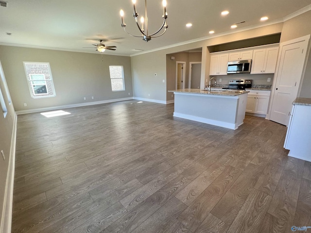 kitchen with dark wood-style flooring, crown molding, appliances with stainless steel finishes, an island with sink, and baseboards