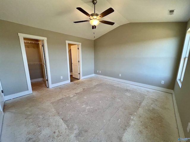 unfurnished bedroom with ceiling fan, visible vents, baseboards, vaulted ceiling, and a walk in closet