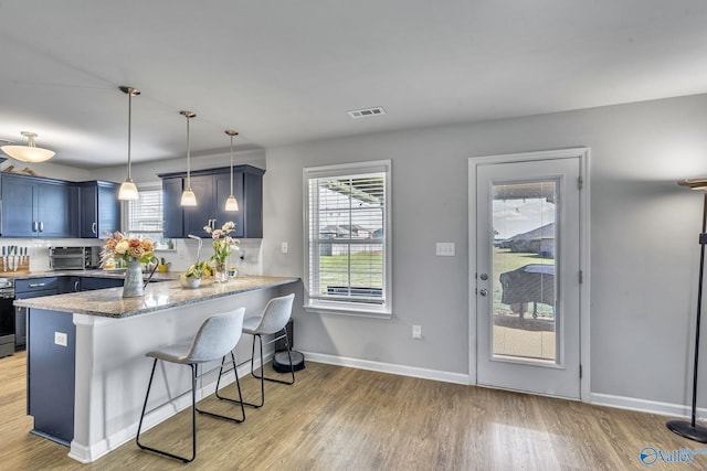 kitchen with pendant lighting, a breakfast bar, light hardwood / wood-style floors, blue cabinets, and kitchen peninsula