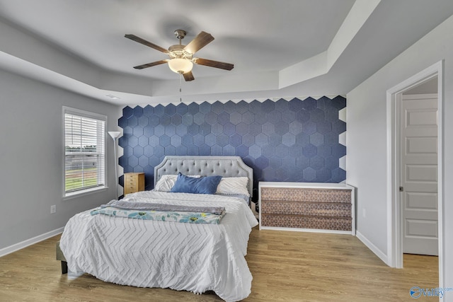 bedroom featuring a tray ceiling, hardwood / wood-style flooring, and ceiling fan