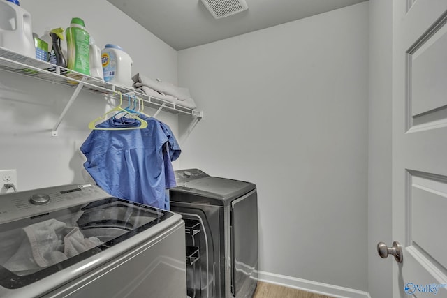 clothes washing area featuring wood-type flooring and washing machine and clothes dryer