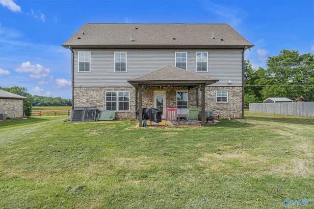 rear view of property with central AC and a yard