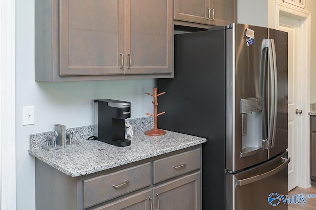 kitchen with light stone countertops and stainless steel fridge