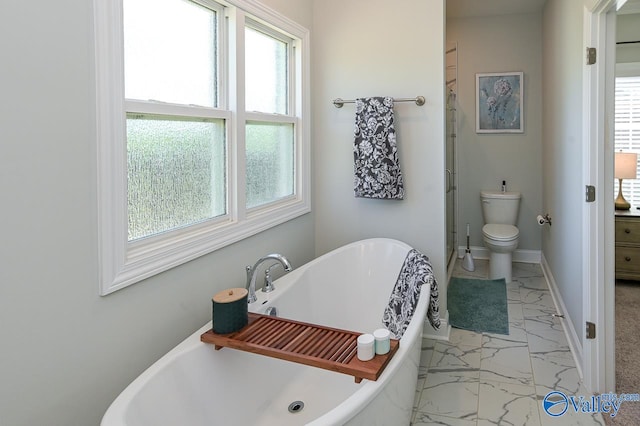 bathroom with a healthy amount of sunlight, tile patterned floors, toilet, and a tub