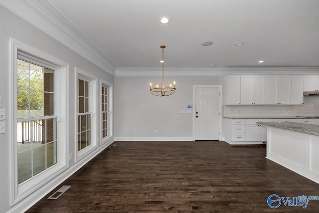 kitchen with dark wood-type flooring, white cabinets, crown molding, backsplash, and decorative light fixtures