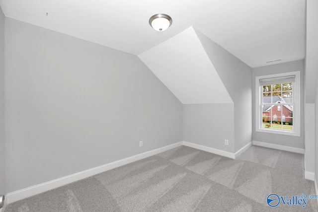 additional living space featuring light carpet and vaulted ceiling