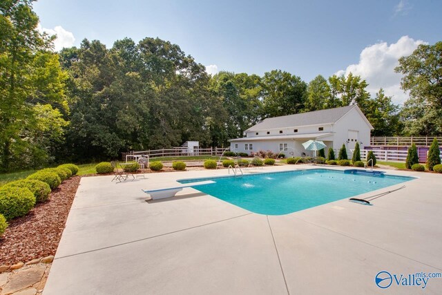 pool with fence, a patio, and a diving board