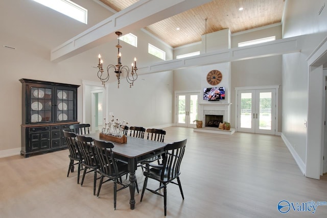 dining area featuring a towering ceiling, a chandelier, wooden ceiling, french doors, and light wood-style flooring