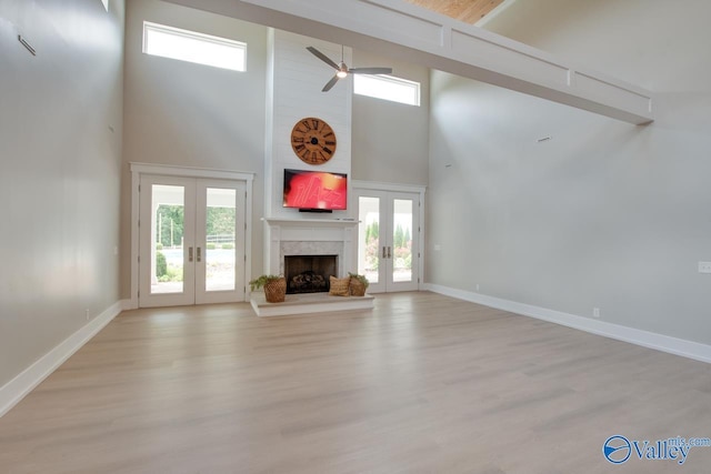 unfurnished living room with a high end fireplace, a healthy amount of sunlight, french doors, and a towering ceiling