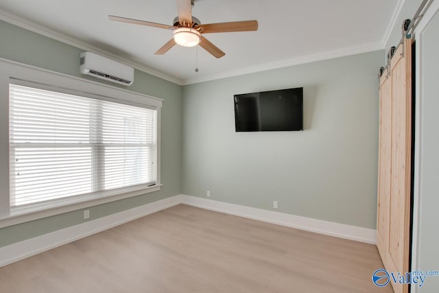 interior space featuring crown molding, baseboards, an AC wall unit, a barn door, and light wood finished floors