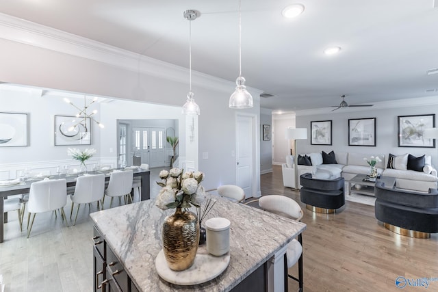 dining space featuring ceiling fan with notable chandelier, ornamental molding, and light hardwood / wood-style flooring