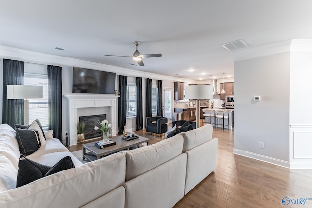 living room featuring ceiling fan, light hardwood / wood-style floors, and crown molding