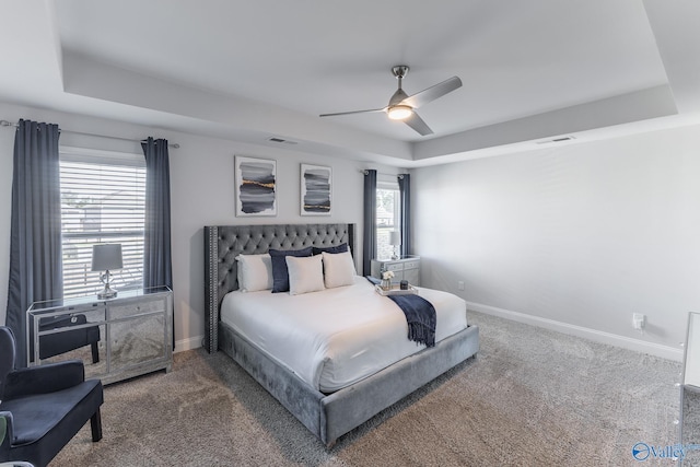 carpeted bedroom featuring ceiling fan and a raised ceiling