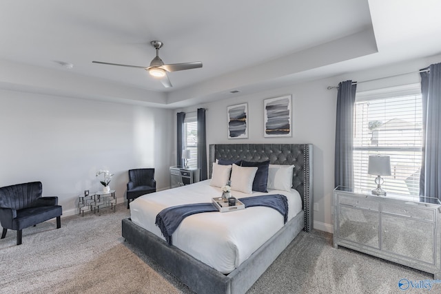 carpeted bedroom featuring a raised ceiling and ceiling fan